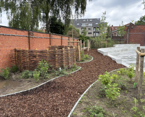 een hoekje van de nieuwe speelplaats met wandelpad, vlechtwerk en arena met betonnen zitranden